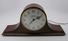 an old clock is sitting on a white surface with wires coming from the top and bottom