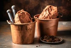 two copper buckets filled with ice cream next to each other on a metal table