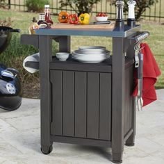 an outdoor kitchen cart with plates and utensils on it