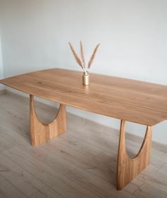 a wooden table sitting on top of a hard wood floor next to a white wall