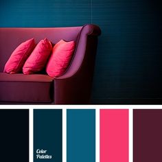 a red couch sitting in front of a blue wall with pink and green pillows on it