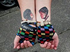 two people with tattoos on their arms holding hands in the shape of mittenss