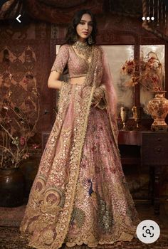 a woman in a pink and gold lehenga