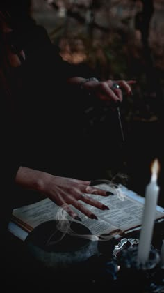 a person sitting at a table with some candles in front of them and an open book on the table