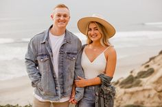 a man and woman standing next to each other near the ocean