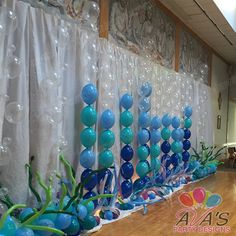 balloons and streamers are on the wall in front of a party backdrop with mermaid tails