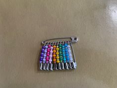 a bunch of colorful beads sitting on top of a metal bar broochle,