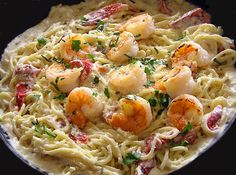 a pan filled with pasta and shrimp on top of a wooden table