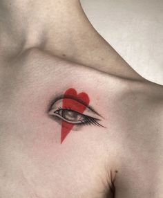 a woman's chest with a red heart and eye tattoo on the left side