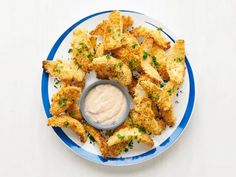 a white plate topped with fried food next to a small bowl of ranch dressing on top of it