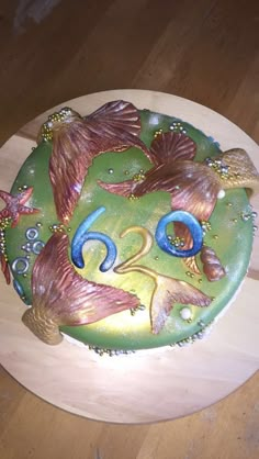 there is a cake that looks like a fish on top of a wooden board with sea shells