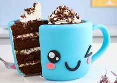 a blue mug with a slice of cake in it and the cup has chocolate frosting on top