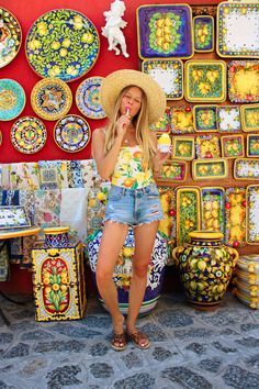 a woman wearing a straw hat standing in front of colorful plates