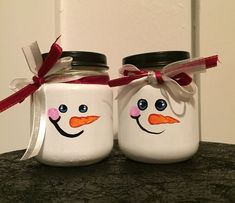 two snowmen painted on mason jars with red ribbon