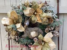 a christmas wreath with gold and silver decorations on top of it next to a wooden fence