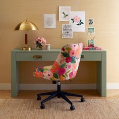 a desk with a chair and pictures on the wall above it, along with a rug