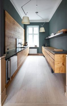 an open kitchen and dining area with wooden cabinets, counter tops, and floor to ceiling windows