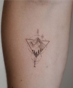 a small tattoo on the back of a woman's left arm with mountains and trees