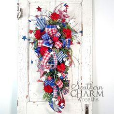 a patriotic wreath hanging on the side of a white door with red, white and blue decorations