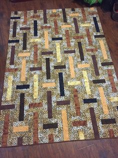 a brown and black area rug sitting on top of a hard wood floor next to a potted plant