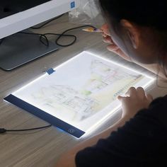 a woman is drawing on a light box