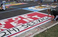 a man is painting the side of a parking lot with spray paint and sidewalk markings