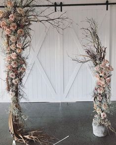 two vases filled with flowers on top of a black floor next to a white wall