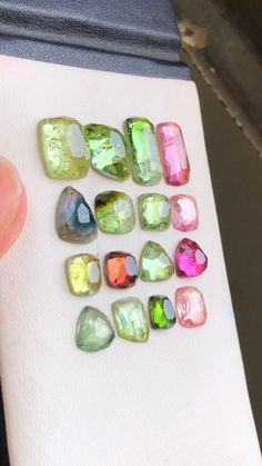 a person holding a piece of paper with different colored stones on it