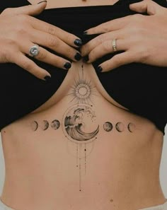 a woman's stomach with the sun and moon tattoos on her back, while holding her hands over her chest