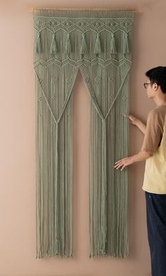 a man standing in front of a curtain with fringes on it and pointing to the side