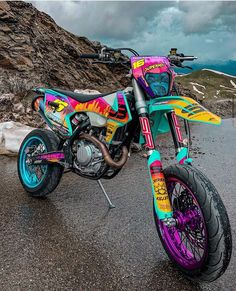 a colorful dirt bike parked on the side of a mountain