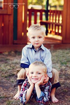 two young boys are sitting on the ground