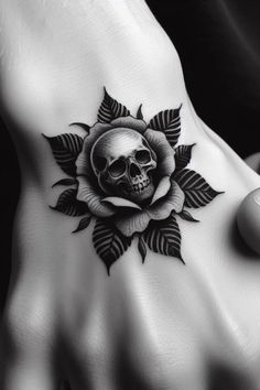 a hand with a skull and rose tattoo on it