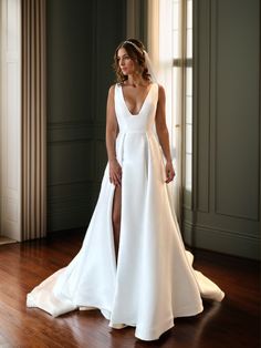 a woman in a white wedding dress standing on a wooden floor with her legs crossed