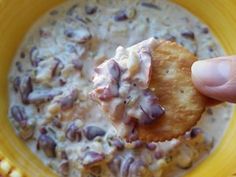 a hand holding a cracker over a bowl of food