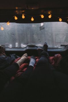 two people laying in the back of a truck with their feet propped up on blankets