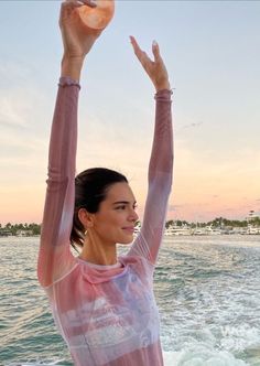 a woman standing on top of a boat holding her arms in the air