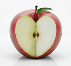 an apple cut in half with a green leaf sticking out of the center, on a white background