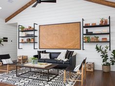 a living room with black and white furniture, wood flooring and open shelving