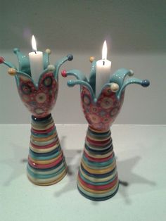 two colorful vases with lit candles in them