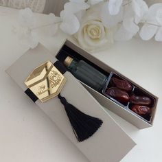 an open box with some tassels in it on a table next to flowers