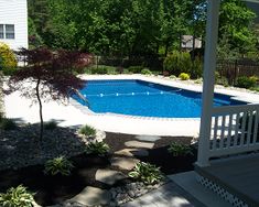 an above ground pool surrounded by landscaping and trees