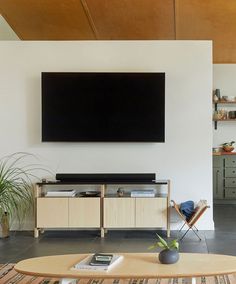 a flat screen tv mounted on the wall above a coffee table in a living room