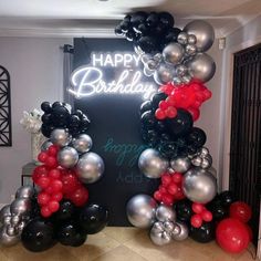 an arch made out of balloons with the words happy birthday written on it in silver and black