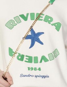 a person holding a gold chain with a starfish on the front and back of their shirt