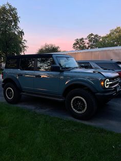 an suv parked in a parking lot next to other cars and trucks at dusk or dawn