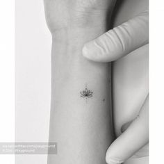 a woman's wrist with a small lotus tattoo on the left side of her arm