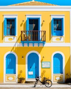 a bike parked in front of a yellow building with blue shutters and balconies