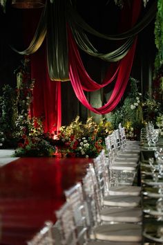 the tables are set with clear chairs and red draping over them for an elegant event