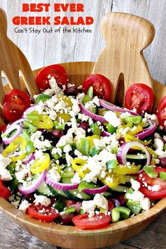 a salad in a wooden bowl with tomatoes, onions and feta cheese on top